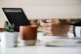 Hands with phone and laptop