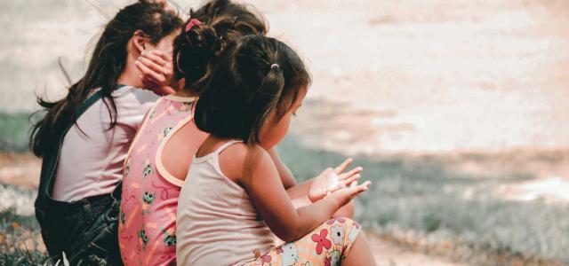 Children sitting on a bench together.